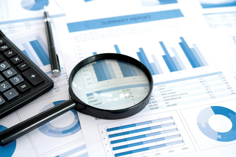 Magnifying glass with business report on financial advisor desk